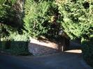 Driveway to Elibank Court.
High brick wall with ivy, trees behind, driveway rises as it curves to the left.