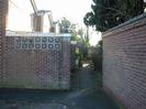 Path to Western row of houses.
High walls, decorative blocks, and wrought-iron gate.