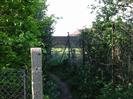 Footpath junction.
Chainlink fences and bushes.
Fence and building in the distance.
