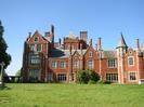The south face of Taplow Court.
Very large house of red brick with stone details.
Many decorative chimney stacks.
Tower with loopholes and conical roof.