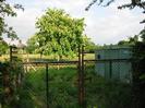 Metal gates with low building and Horse Chestnut tree beyond.