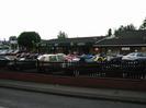 Car showrooms and forecourt of SGT.
Cars on forecourt.
Low wall with fence.
Pavement and road in foreground.