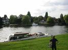 River Thames.
Grassy bank with people and moored boat.
Houses and boats on far bank.
