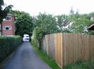 Tarmac driveway from Hermitage House to the Bath Road.
Privet hedge on left with three-storey brick-built flats behind it.
Large trees overhanging at junction with Bath Road.
Wooden slat fence on right.