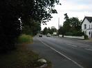 Looking east on the A4 Bath Road.
Dark trees on left.
White house on right.
Hotel and school signs in the distance.