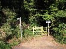 Footpath entrance with banks of trees on each side.
Wooden kissing-gate.
Public Footpath sign.
Byelaws notice.