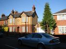 Pair of houses on the left with red brick and pebbledash.
Garage and house on right of brick with white windowframes.