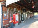The main station building on platform 4.
Red brick with arches detailed in light stone.
Cantilevered canopy with decorative wooden edging.
Two red ticket machines with graffiti on sides.
BT phone booth.
Sign on near wall: "This platform for trains to Slough and London. Over footbridge for trains to Reading and West".
Signs: "4", "Taplow", "Waiting room", "Ladies", "Tickets", "Way out".
Digital station clock.
Information displays.
Cameras.
Metal seats.