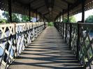 Covered footbridge with iron lattice sides.
Striking patterns on bridge deck made by setting sun.