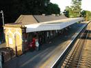 Main building of Taplow Station seen from the footbridge.
Red brick with light stone details in arches.
Dark slate roof.
White canopy over platform.