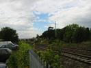 Railway with metal fence and car-park on left.
Taplow Station in the background.
Dark trees on right with cellphone mast.
