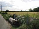Footway on left.
Metal farm gate blocked by large log.
Field on right.