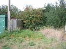 Green roadside cabin on left.
Gate to electricity substation.
Scrubby area and hedge.