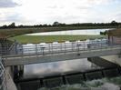 Jubilee River weir structure.
Concrete footbridge with control gear.
Row of yellow cylindrical floats holding back a mass of green weed.