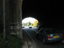 Looking west through the arch of the railway bridge.
Trees and buildings visible on the far side.
Cars on road.