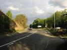 Looking east on the A4 Bath Road.
Retaining wall and embankment on left.
Trees on right.
Street-lights and road-signs.