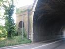 Arched brick railway bridge across road.
The small arch on the left is now fenced off, but in the early days of the Great Western Railway this led to a temporary station on top of the embankment where passengers would alight to cross the Thames before the river bridge was completed.
Tree and street-light on left.