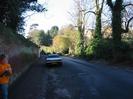 Looking West on rectory Road. Jane taking notes. High wall on left,
parked car, ivy hedge and trees on the right.