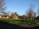 Eastern part of Village Green. Village Hall on the left, and houses in High Street visible through the trees.