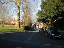 Looking North up High Street.
Village Green on the left, with large trees.
Entrance to St Nicolas Church on the right.