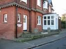 St Nicolas House.
Red brick building, tile-hung on the first-floor level.
White painted entrance with fleur-de-lys.