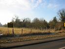 Field with sign advertising the Oak and Saw public house.
Wire fences, and trees in the background.