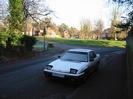 Rectory Road.
Village Green and High Street in the background.
Parked car.
Road signs and street light.