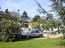 Car park with garages and houses beyond.
Viburnum hedge. Street light. Parked cars.
Branch of Cedar tree.
Mature Cedar trees visible behind houses.