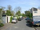 Looking East along Cedar Chase.
Garages on the left, rear of house 17 on the right.
Parked cars.
St Nicolas Church spire visible in the distance.