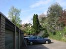 Garages on the left.
Parked cars.
Houses in the distance.