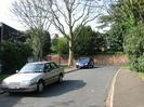 The entrance to Cedar Chase.
High brick wall on the other side of Rectory Road.
Parked cars and trees.