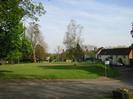 Village Green.
St Nicolas Church spire visible through trees on left.
Rectory Road houses on right.
Sign pointing to Village Hall car park.