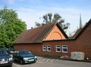 The back of the Village Hall.
Red brick building with tile roof.
St Nicolas Church spire visible over the roof on the right.