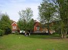 The North-East corner of the Village Green.
Children playing.
Houses on High Street behind hedge and trees.