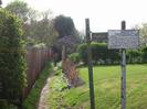 Entrance to public footpath at top of High Street.
Wooden fence on the left of footpath.
Footpath sign and Cycling Prohibited sign.
Young Beech hedge and lawn on the right.