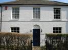 Victoria Cottage: white house with dark blue door and sash windows.
Grey slate roof.
Hedges and wrought-iron gate.