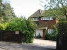 The Orchard: Tile-hung house with white windows.
Dark wooden fence with trees behind.