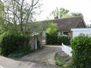 Pan's Place: bungalow with concrete tile roof.
High walls with ivy and wrought-iron gate.
White paling fence.
Garage with white door.