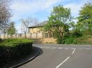 Hill Farm: large house built from sandy-coloured bricks, with white windows and grey slate roof.
Wall with fence panels.
Road junction.
Hedges.