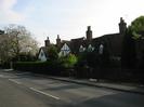 Road with cottages seen against the light.
White walls with black timbers, and red tile roofs.