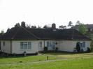 Bungalow with cream-painted walls and tile roof.
Grass area in front, with hydrant marker.
Houses in Buffins visible on the right.