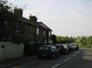 Looking North on Hill Farm Road.
Row of houses on the left.
Parked cars.
Telephone wires.