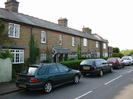 Row of houses on West side of Hill Farm Road.
Dark sandy-coloured bricks with decorative rows in red brick.
Slate roofs.
Hedge and parked cars.