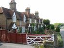 Row of cottages.
Dark sandy-coloured bricks with decorative patterns in red brick.
Clay tile roofs.
Diamond-leaded windows.
Date AD 1853 set into centre of row in red brick.
Wooden fence and white five-bar gate in foreground.