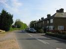 Looking South on Hill Farm Road.
Trees and bus stop on the left.
Houses on the right.
Parked cars.