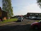 Looking South into Buffins.
Houses to left and right.
Grass and tree on the left.
Parked cars.