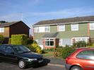 Two groups of houses.
Tile-hung at first floor level.
Large windows.
Dark roofs.
Parked cars.