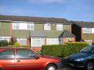 Row of houses.
Hedges in front.
Parked cars.