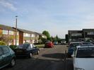 Houses to left and right.
Gap with hedge and trees at end of road.
Parked cars.
Street lights.