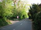 Looking South on Hill Farm Road.
Entrance to Hitcham Grange on the left, with estate agent's sign.
Hedges and trees on both sides of road.